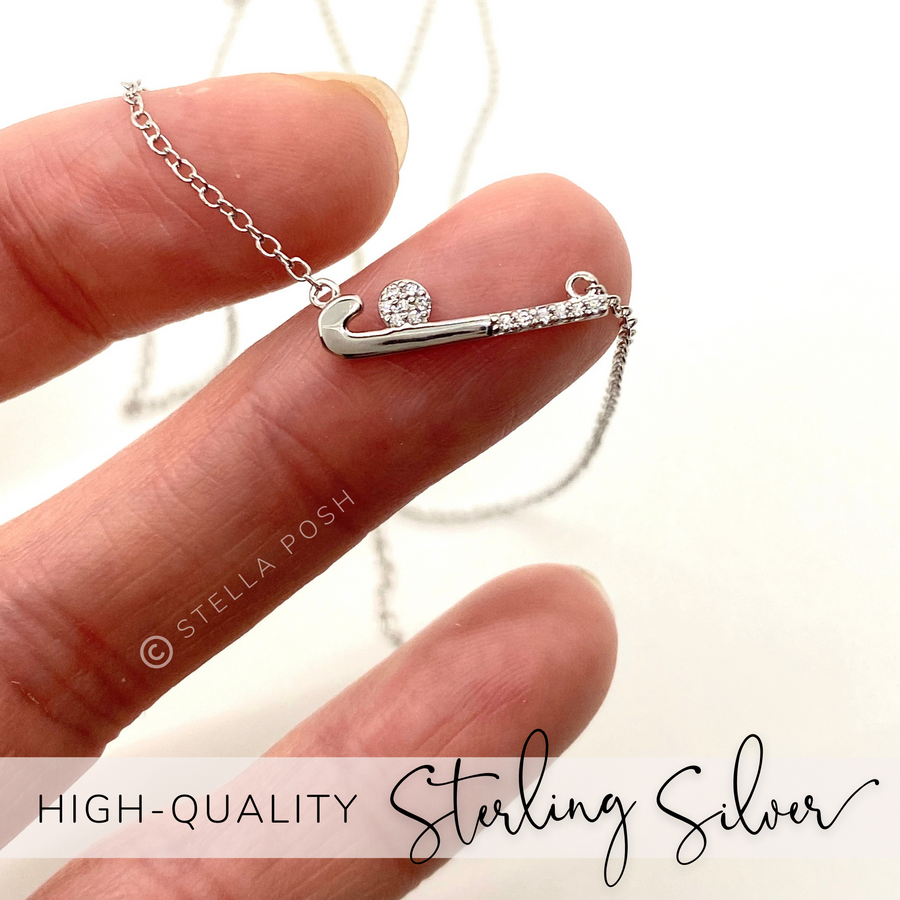Dainty .925 Sterling Silver Field Hockey Necklace with premium cubic zirconias in a pavé setting, held in hand for scale.