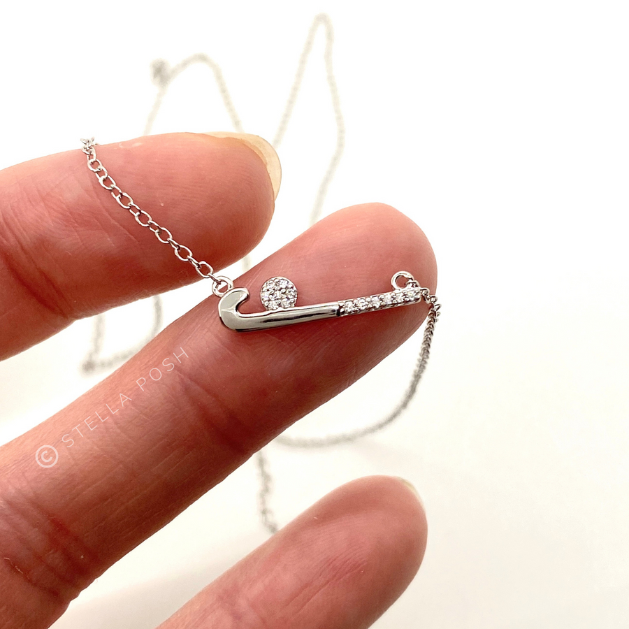 Dainty .925 Sterling Silver Field Hockey Necklace with premium cubic zirconias in a pavé setting, held in hand for scale.
