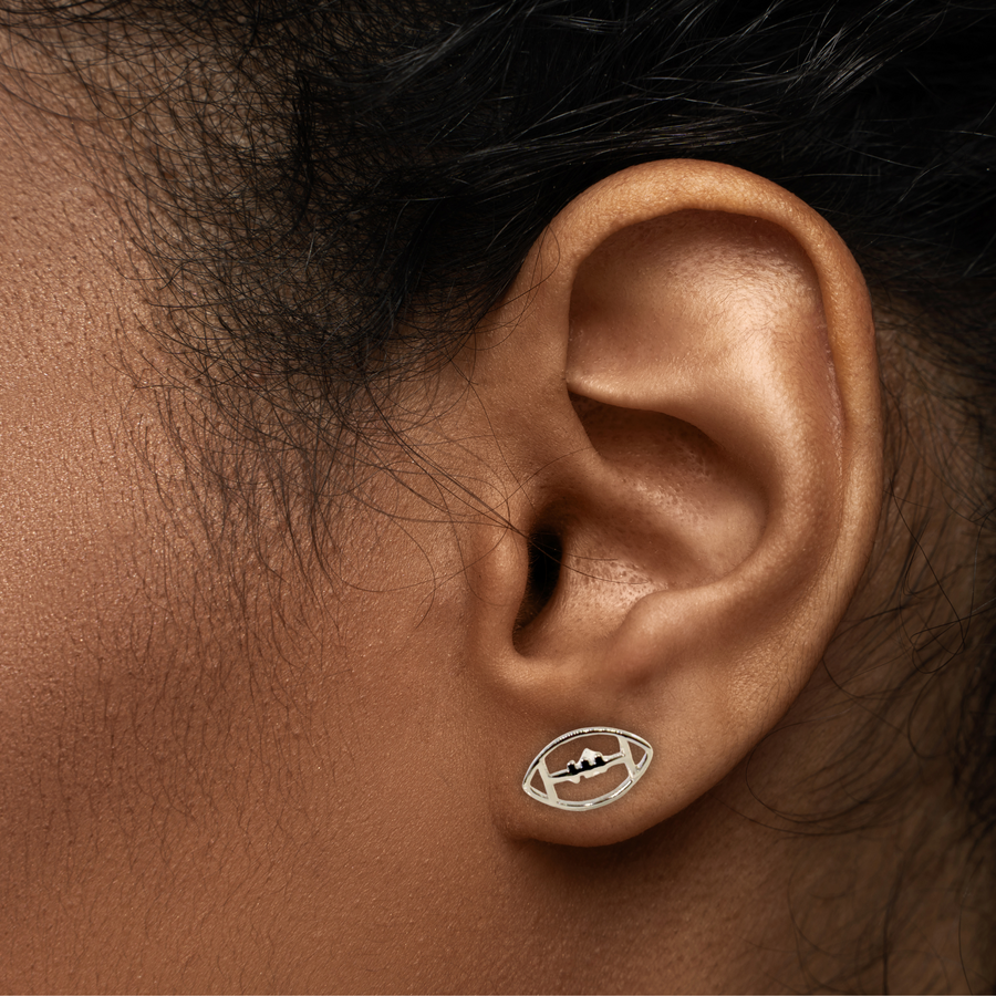 Model wearing tiny silver football earring.