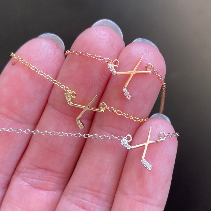 Dainty .925 silver Ice Hockey necklace with premium cubic zirconia stones in a pavé setting, held in hand forscale.