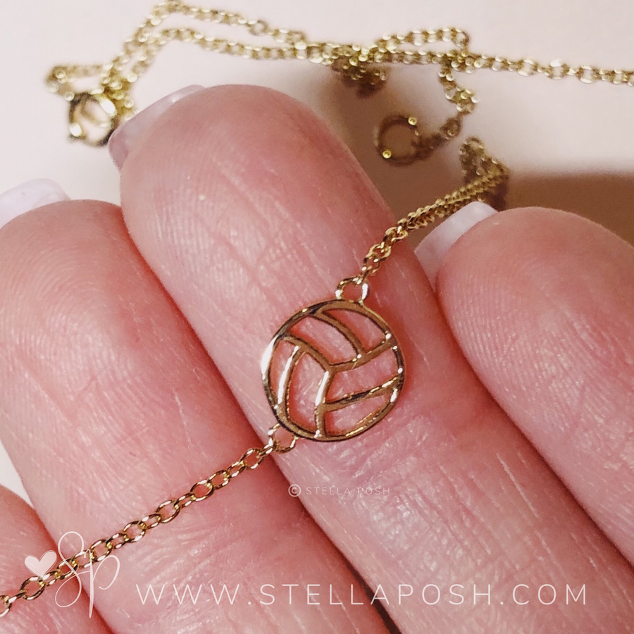 Tiny, dainty .925 silver Volleyball Necklace in gold, held in hand for scale.