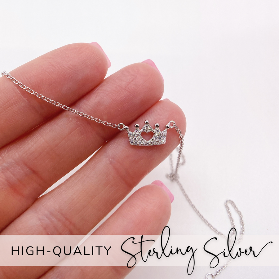 Dainty .925 sterling silver Tiny Princess Crown Necklace with premium cubic zirconias, held in hand for scale.