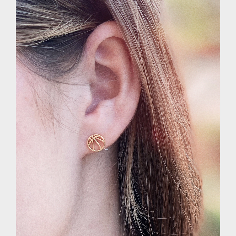 Model wearing Tiny .925 silver Basketball Earrings in gold.