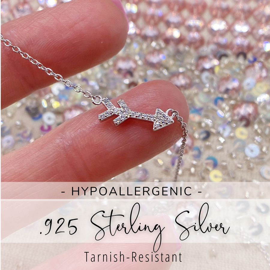 Tiny Arrow .925 sterling silver necklace with premium cubic zirconias in a pavé setting held in hand for scale.