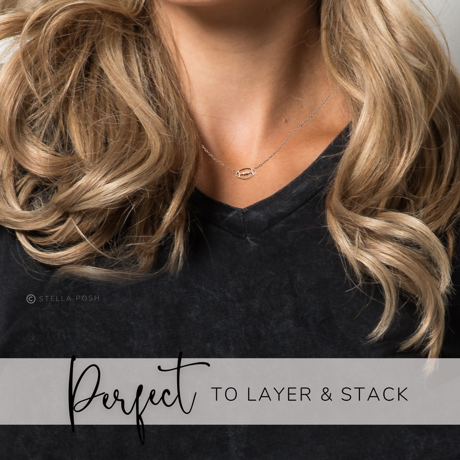 Model wearing .925 silver Tiny Football Necklace, perfect to layer and stack.