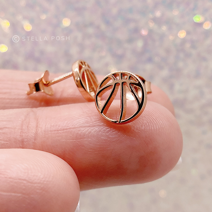 .925 Sterling Silver Basketball Earrings in gold, shown on finger for scale.