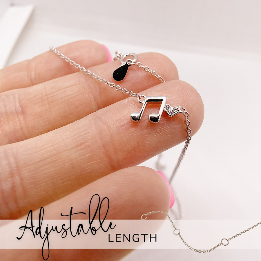 Adjustable length Tiny Music Note .925 silver necklace with premium cubic zirconias, held in hand for scale.