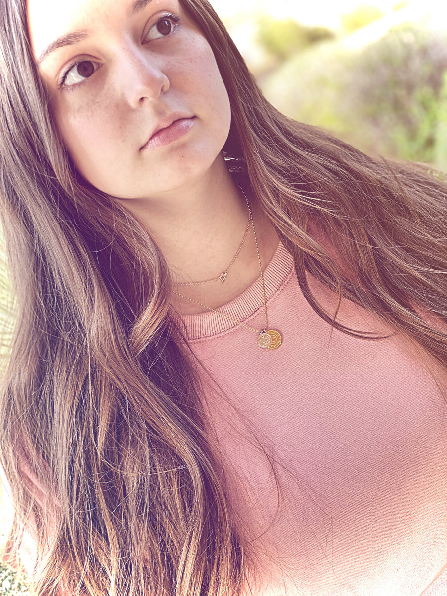 Teen Model wearing .925 silver Music Note Necklace with premium cubic zirconias, layered with a charm necklace.
